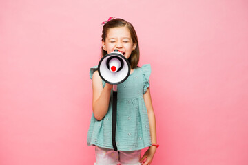 Cheerful kid giving a loud message using a megaphone