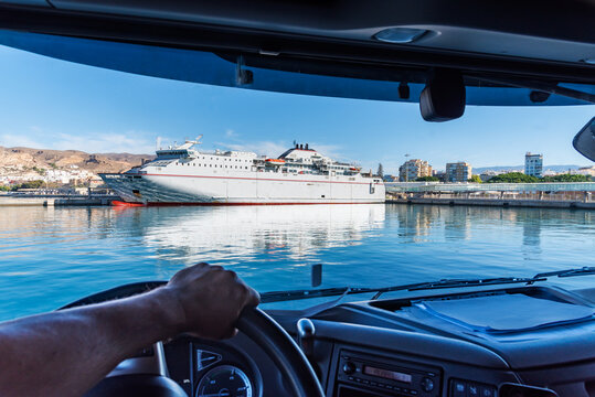 View of a ferry docked in port from the cabin of a truck as it turns around in a narrow dock.
