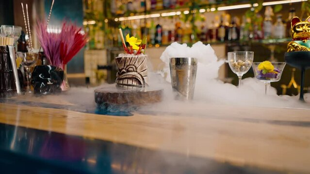 close-up fresh alcoholic tasty cocktail stands on the bar near which liquid nitrogen spreads beautiful and effective serving of the drink in a bar