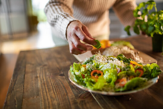 Middle Aged Woman Preparing A Healthy Salad With Organic Fruits And Vegetables At Home And Decorating A Plate