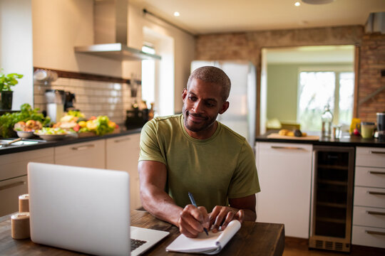 Middle aged african american male food nutritionist and blogger talking to his client over a video call in his kitchen