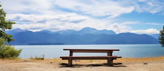 Obraz premium Sandy beach picnic table with lake mountain and blue sky view