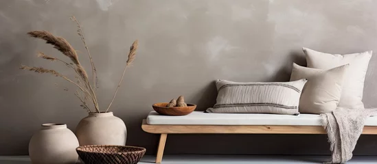 Abwaschbare Fototapete Boho-Stil The ethnic composition of a stylish living room with a grey concrete wall and cozy apartment decor including a beige bowl bench and elegant personal accessories