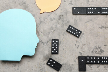 Paper human head with speech bubble and dominoes on grunge background. Logic concept