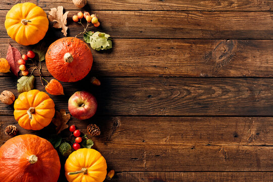 Frame border of pumpkins, fall leaves, berries, apple on wooden table. Thanksgiving, Halloween, Autumn, Harvest concept. Flat lay composition, top view, copy space