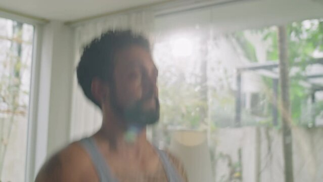 Muscular man in sportswear jumping rope at home while having cardio workout or warming up