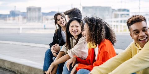 Young group of happy students sitting together outside while hanging out. Millennial people enjoying a conversation. Copy space for text