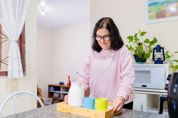 Brazilian Coffee Time at Home: smiling mature Brazilian woman setting the table for an afternoon snack at home