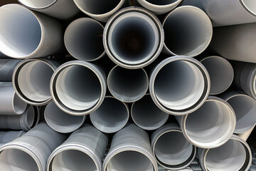 Stack of PVC canalization pipes plumbing tube on a hardware store stock. Gray plastic pipes. Industrial for plumber. Construction Materials, selective focus