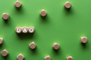 There is wood cube with the word DAO. It is an abbreviation for Decentralized Autonomous Organization as eye-catching image.