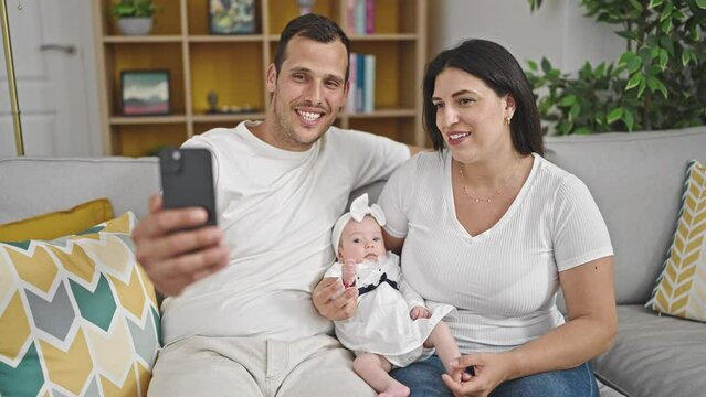 Family of three taking selfie sitting on the sofa at home