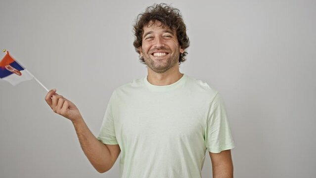 Young hispanic man smiling confident holding serbian flag over isolated white background