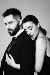 Handsome bearded man with sexy lady on grey background. Black and white effect