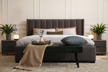 Stylish bedroom interior with large comfortable bed and ottoman