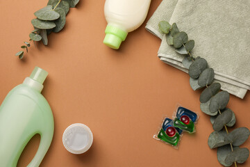 Flat lay composition with bottles of fabric softener and laundry detergent pods on brown...