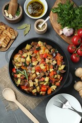 Delicious ratatouille and ingredients on grey table, flat lay