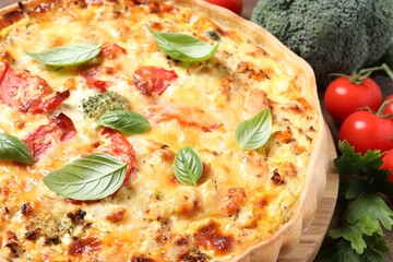 Tasty cheese quiche and ingredients on table, closeup