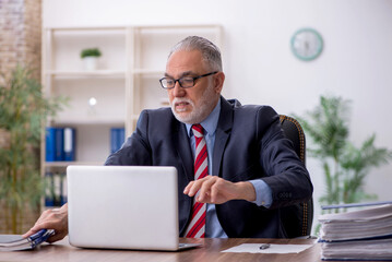 Old male employee working in the office