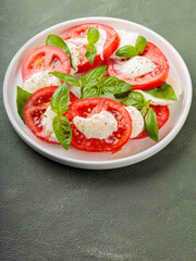 Fresh italian caprese salad with mozzarella and tomatoes on white plate. Top view. Copy space