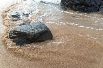 Sea waves crashing on the black rocks of the seashore.