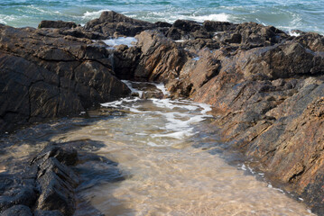 Sea water in the form of waves hitting the rocks on the beach.