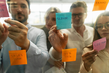 Group of business people using sticky notes, agile methodology for productivity working together in modern office. Colleagues planning strategy, startup, communication at workplace. Teamwork, scrum  - obrazy, fototapety, plakaty