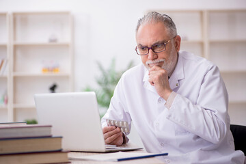 Old male doctor in telemedicine concept