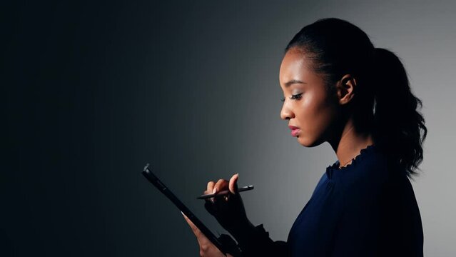 Young Black woman using a tablet PC in dark room.