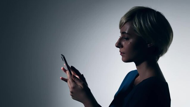 Young Caucasian woman using a smart phone in dark room.