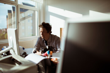 Young photographer going through his camera at his desk in the office office