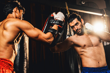 Asian and Caucasian Muay Thai boxer unleash punch in fierce boxing training session, delivering...