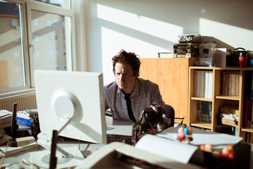 Young photographer going through his camera at his desk in the office office