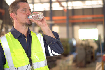 Factory technician or engineer taking a break after have a work, worker drinking water in bottle.
