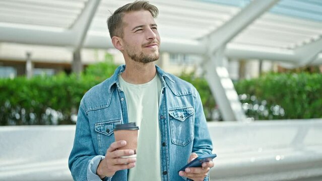 Young caucasian man using smartphone drinking coffee at park