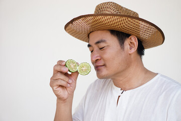 Handsome Asian man holds  kaffir lime fruit to smell. Concept, herbal fruit, aromatherapy, Kaffir lime essential oil has properties to help relieve stress,anxiety and dizzy. feels fresh when smelling.