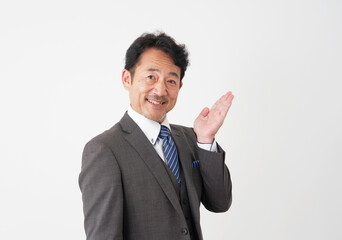 手の平で右側を指す中年のビジネスマン　白背景