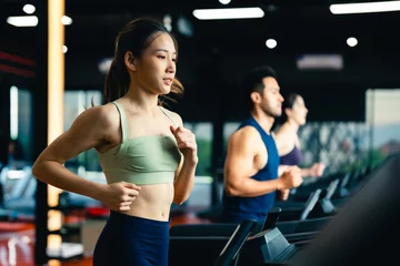 Foto op Plexiglas Fitness Fit young woman and man running on a treadmill during a workout class at fitness gym