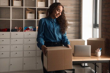 Young Asian curly-haired logistics worker packs goods, collects parcels, puts things in a carton box, prepares a parcel for shipment, transports, collects donations, business owner, delivery