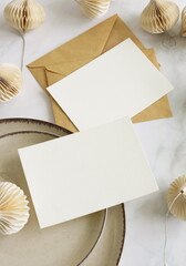 Cards mockup, envelopes and christmas garland top view on white marble background with copy space....
