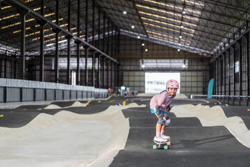 asian child skater or kid girl fun playing skateboard or smile ride surf skate in indoor pump track...