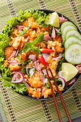 Khao Pad Naem Salad Fried rice ball with fermented pork, vegetables and herbs closeup on the plate on the table. Vertical top view from above