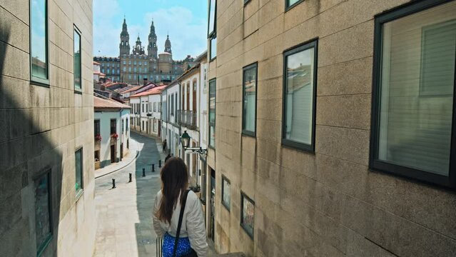 A tourist girl with a bag looking at Cathedral of Santiago de Compostela Spain. A female walking towards the famous Spanish Basilia a World Heritage Site in Galicia, Spain.
