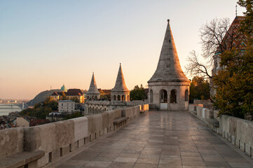 Old buildings with towers illuminated by the setting sun and stone pavement on the promenade of the Fisherman's Bastion in Budapest, Hungary