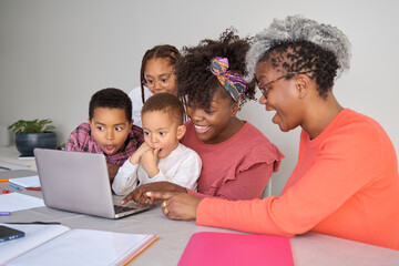 Happy african horizontal extended family look at laptop screen surprised at home.