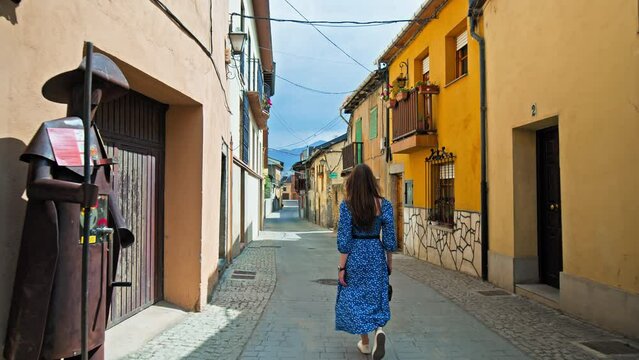 Beautiful girl in a dress with a camera walking on the old streets of Ponferrada. A tourist female holding a camera on colourful historical streets of Ponferrada City in northwestern Spain.