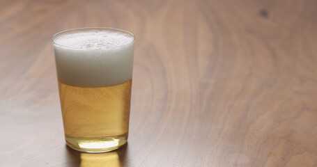 Light lager beer in thin wall glass on wood table with copy space