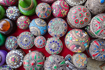Marrakech, Morocco - Feb 10, 2023: Enamel and silver Moroccan Berber pill boxes on sale in Marrakech souk market