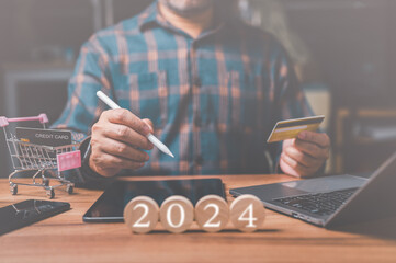 A man holds a credit card in his hand, contemplating his online shopping spree for the upcoming New...