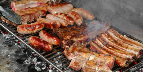 Roasted sausages and pork ribs on the grill on the barbecue
