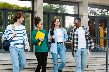 Group of Latin and African American college student friends walking outside University building  - obrazy, fototapety, plakaty